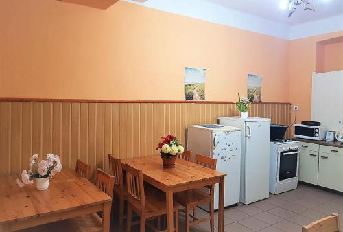 a kitchen with wooden tables and white appliances at Muskátli Vendégház in Parádfürdő-Peres