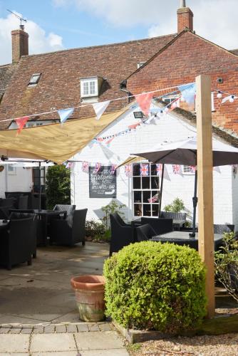 a patio with an umbrella and chairs and a building at The Bell Hotel Woburn By Greene King Inns in Woburn