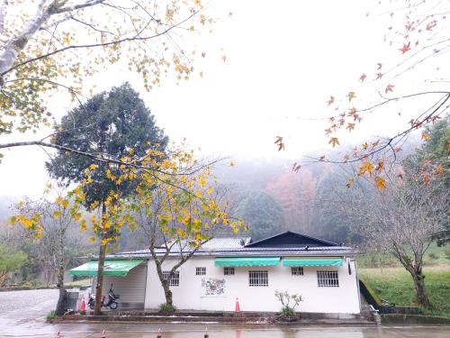 a white house with a tree in front of it at 赤科山櫻之谷咖啡民宿 in Chiu-t'ien