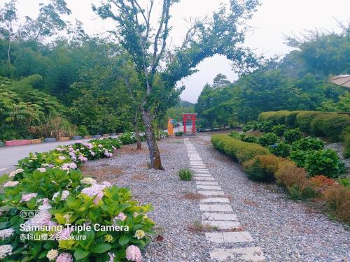 a pathway with flowers and a tree on the side of a road at 赤科山櫻之谷咖啡民宿 in Chiu-t'ien