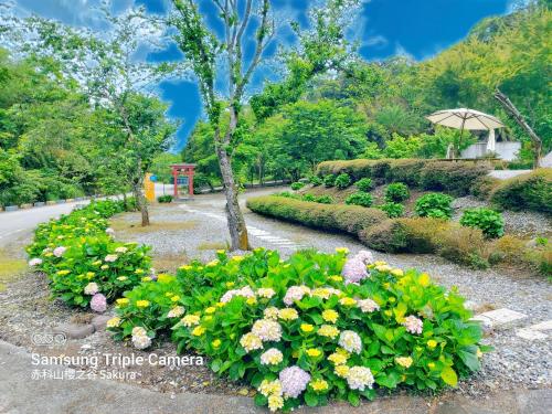 a garden with flowers and an umbrella on a road at 赤科山櫻之谷咖啡民宿 in Chiu-t'ien