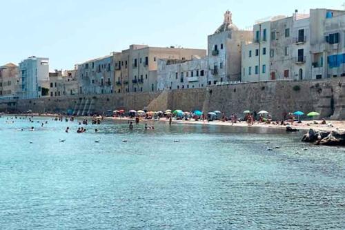 a group of people on a beach with umbrellas at marefuori in Trapani