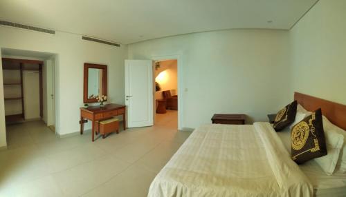 a bedroom with a bed and a table and a mirror at Rose Beach Villas in Durat  Alarous