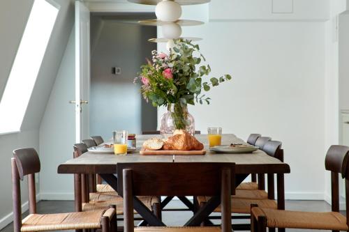 a dining room table with a vase of flowers at LUXURY Penthouse · Private Balcony · Heart of Copenhagen in Copenhagen