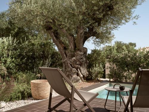 a patio with two chairs and a table next to a tree at Zayn Luxury Villas, a Serene Escape, By ThinkVilla in Zakynthos Town