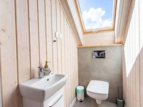 a bathroom with a sink and a toilet with a skylight at Domki Poczekajka in Sasino