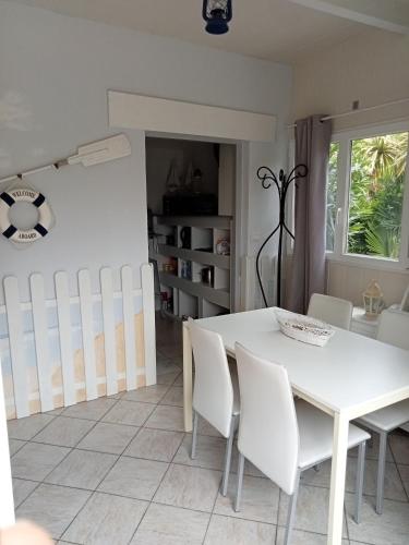 une salle à manger blanche avec une table et des chaises blanches dans l'établissement Charmante maisonnette, à Parentis-en-Born
