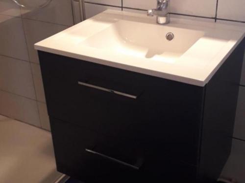 een badkamer met een witte wastafel en een zwarte kast bij Gîte Bourbon-l'Archambault, 4 pièces, 6 personnes - FR-1-489-87 in Bourbon-lʼArchambault