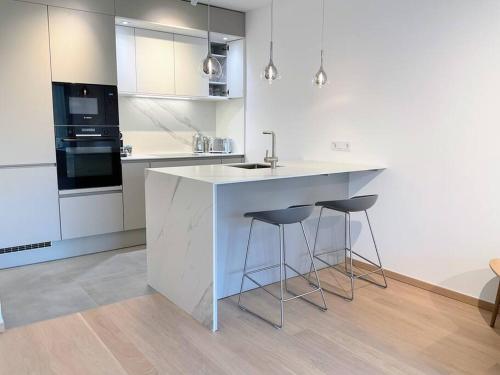 eine weiße Küche mit einer Theke und Stühlen in der Unterkunft Kirchberg Apartment - High End 1 bedroom Apartment with terrace & parking in Luxemburg (Stadt)