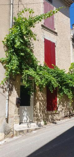 ein Gebäude mit zwei roten Türen und einem Fenster in der Unterkunft Studio en plein cœur de la ville in Mazan