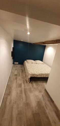1 dormitorio con cama y pared azul en Studio en plein cœur de la ville, en Mazan