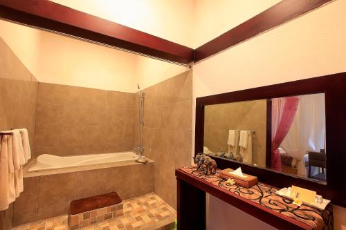 a bathroom with a tub and a sink and a mirror at Lavender Villa & Spa in Kuta