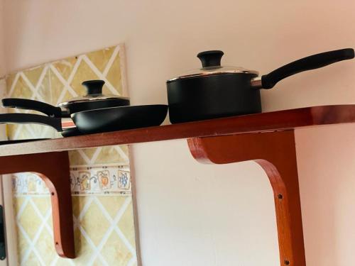 two pots and pans sitting on a wooden shelf at AS Guest House in Libreville