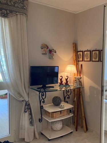 um quarto com uma secretária, uma televisão e uma janela em Villa in spiaggia tra fiori e mare em Torre Mileto