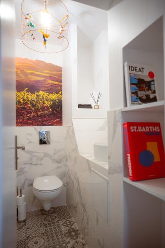 La salle de bains est pourvue de toilettes blanches et d'un lustre. dans l'établissement Le M. Musée du vin - l'appartement, à Paris