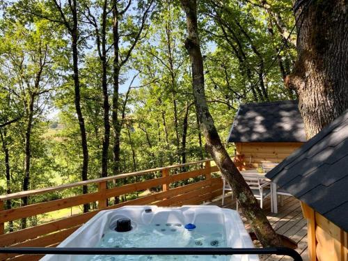 a hot tub sitting on a deck next to a tree at La Cabane perchée de la Mure in Bongheat