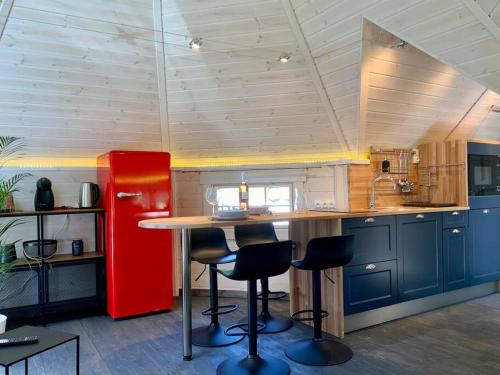 a kitchen with a red refrigerator and a counter with stools at La Cabane perchée de la Mure in Bongheat