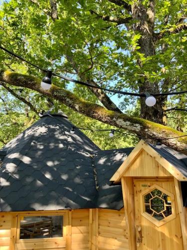 a bird house with a black roof and a tree at La Cabane perchée de la Mure in Bongheat