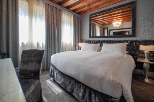 a hotel room with a large bed and a mirror at Papadopoli Hotel Venezia - MGallery Collection in Venice