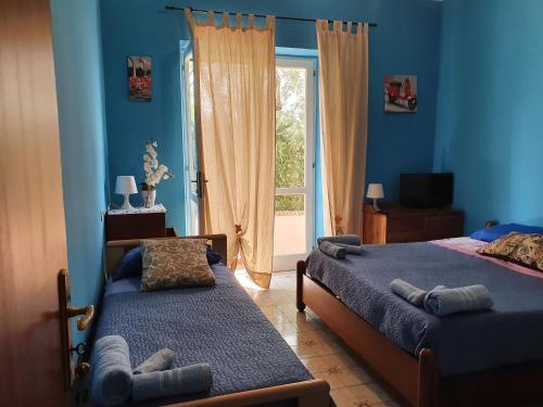a blue bedroom with two beds and a window at La capannina cilento cam 12 in San Marco di Castellabate