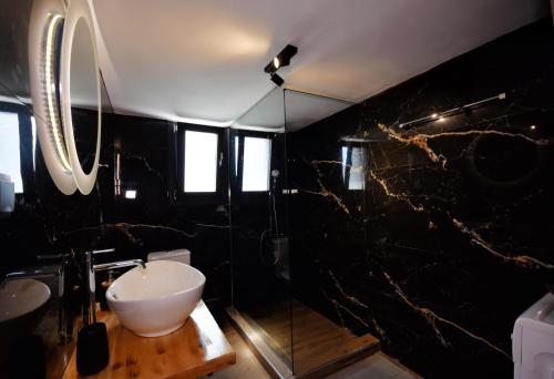 a black bathroom with a sink and a mirror at artemis apartment in Agria