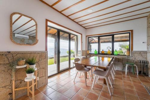 a dining room with a table and chairs and windows at Casa Letrigo in Arcos de Valdevez
