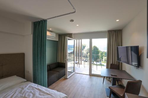 a bedroom with a bed and a tv and a balcony at Casa Grande in Techelsberg am Worthersee