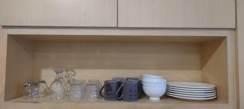 a shelf with plates and cups and other items in a cabinet at Super Comfy BIG SPACE Condo In Imperial Suites Boulevard Mall in Kuching