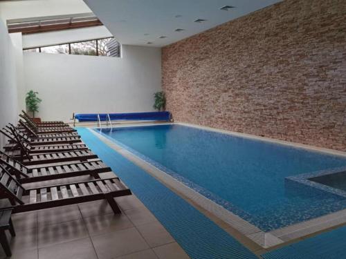 a swimming pool with chairs and a brick wall at LOREA Apartment L000 in Aspen Golf Resort in Razlog