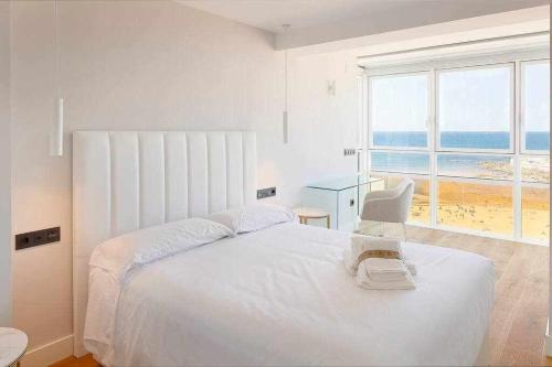 a white bedroom with a large bed and a chair at Argus San Lorenzo By Silastur in Gijón