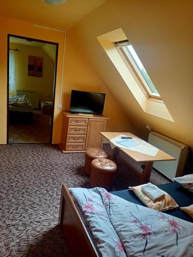 a room with a bed and a desk and a window at Penzion Lukáš in Malá Morávka