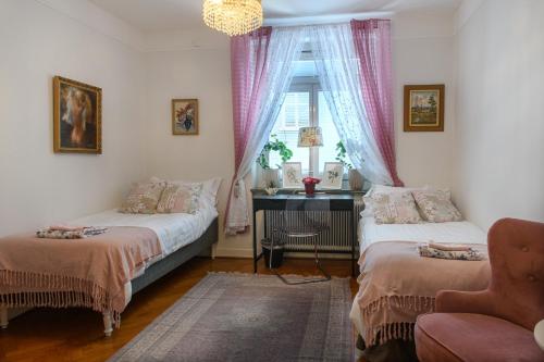 a bedroom with two beds and a desk and a window at HoMade B&B, Gamla Stan in Norrköping