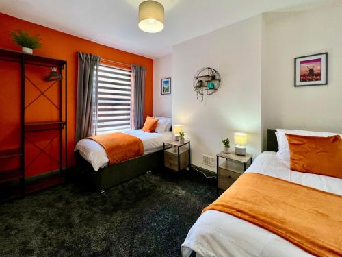 two beds in a room with orange walls at Birkin House - Urban Oasis Townhouse in Nottingham