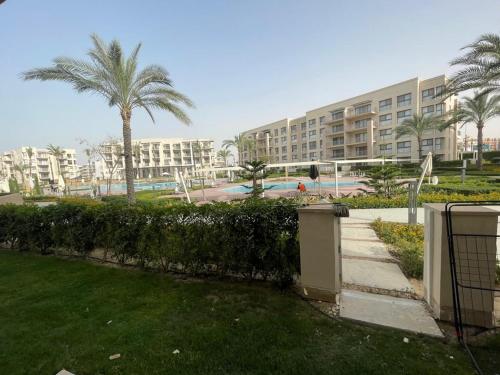 a park with palm trees and a large building at Marrassi Marina spacious chalet in El Alamein