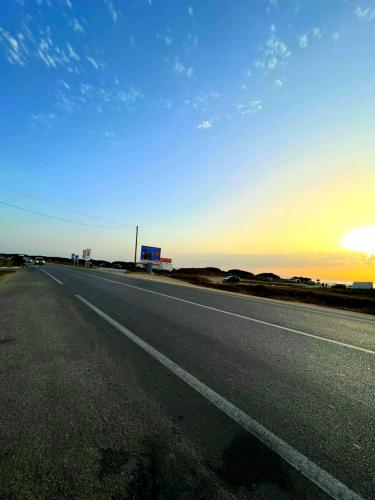 an empty highway with the sun setting in the horizon at Appartement dans résidence à 2 pas de la mer et parking in Tangier