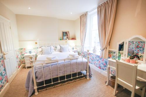 a bedroom with a bed and a dresser and a window at Fleur de Lys Bampton in Bampton