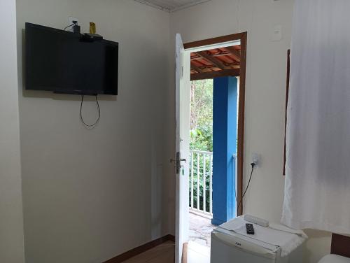 Habitación con TV en la pared y aseo. en Pousada Maravilhas da Serra en Moeda