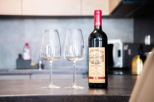 a bottle of wine and two wine glasses on a counter at GLAM apartmán Bučovice in Bučovice