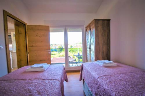 een slaapkamer met 2 bedden en een raam met uitzicht bij Holiday Home Marino in Zmijavci