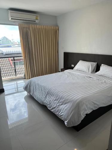 a bedroom with a bed and a large window at Tongyang House Serviced Apartment in Bangkok