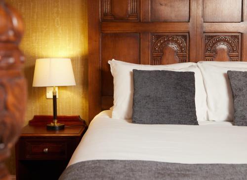 a bedroom with a bed with a wooden headboard and a lamp at Fieldhead Hotel by Greene King Inns in Markfield