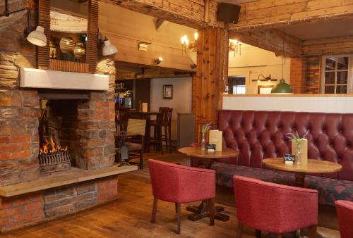 a fireplace in a restaurant with tables and chairs at Fieldhead Hotel by Greene King Inns in Markfield