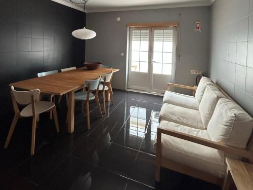 een eetkamer met een tafel en een bank bij Wave - Beach House, Baleal in Baleal