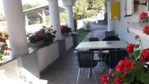a table and chairs on a porch with red flowers at Ferienwohnung Ronja in Stubenberg