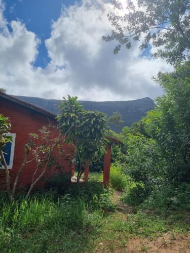 a red house with a tree in front of it at Vila das Acácias in Vale do Capao