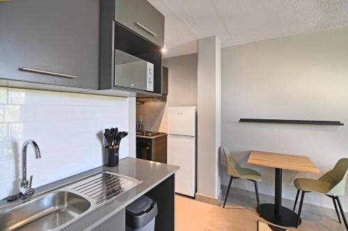a kitchen with a sink and a table with chairs at Circa Aparthotel by Totalstay in Pretoria