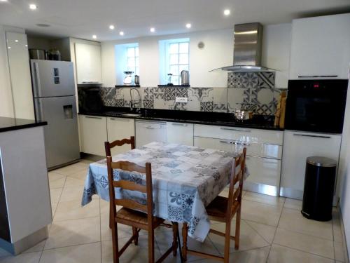 a kitchen with a table and chairs and a refrigerator at La quiétude de St Antoine - piscine privée in LʼIsle-sur-la-Sorgue