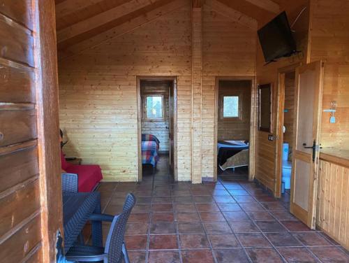 a hallway in a log cabin with chairs and a television at ECOLODGE CABAÑEROS 