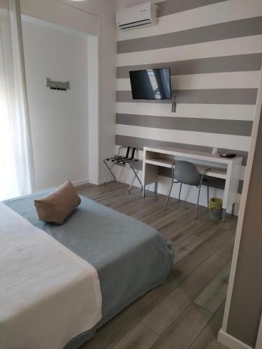a bedroom with a bed and a desk and a television at Le Sculture B&B in Cosenza