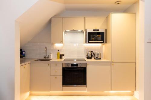 a kitchen with white cabinets and a stove top oven at RÌGH Properties - Luxurious City Centre Three Bedroom Apartment in Edinburgh